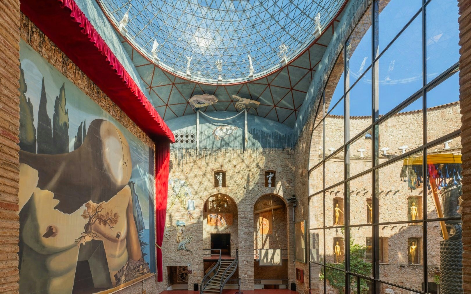 Central stage of the Dalí Theatre-Museum with large surrealist mural and glass dome ceiling.