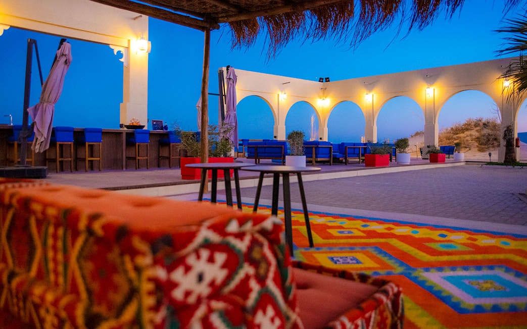 Outdoor seating area at Al Majles Resort with colorful decor and arches at sunset.