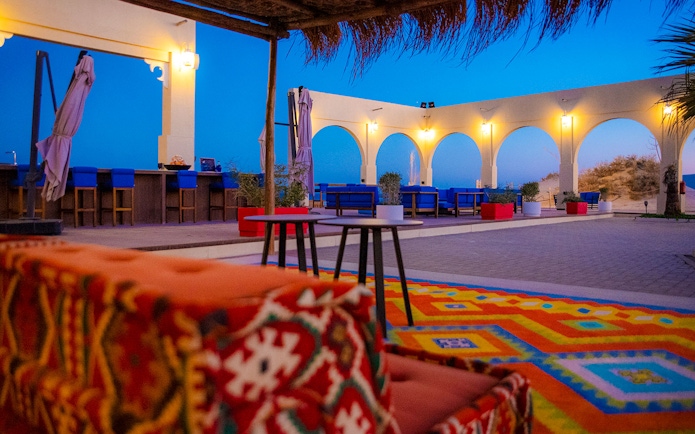 Outdoor seating area at Al Majles Resort with colorful decor and arches at sunset.