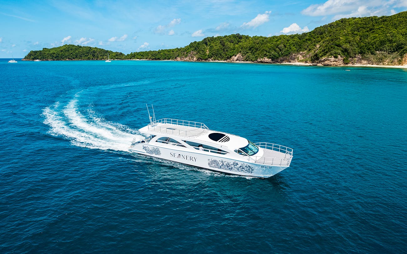 Premium catamaran cruising near Phi Phi Islands, Thailand, with lush green coastline.
