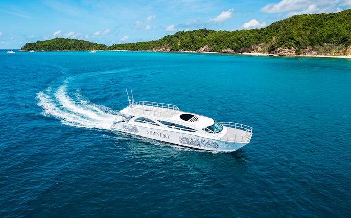 Premium catamaran cruising near Phi Phi Islands, Thailand, with lush green coastline.