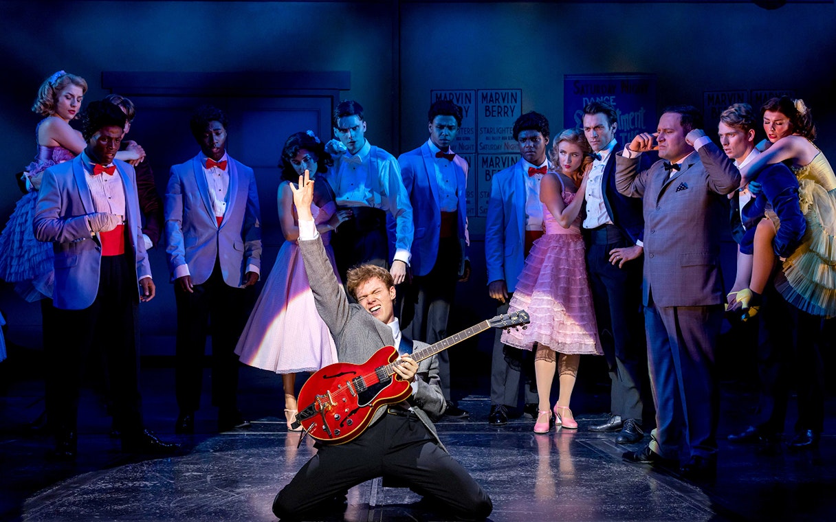 Performer playing guitar on stage during a "Back to the Future" musical scene.