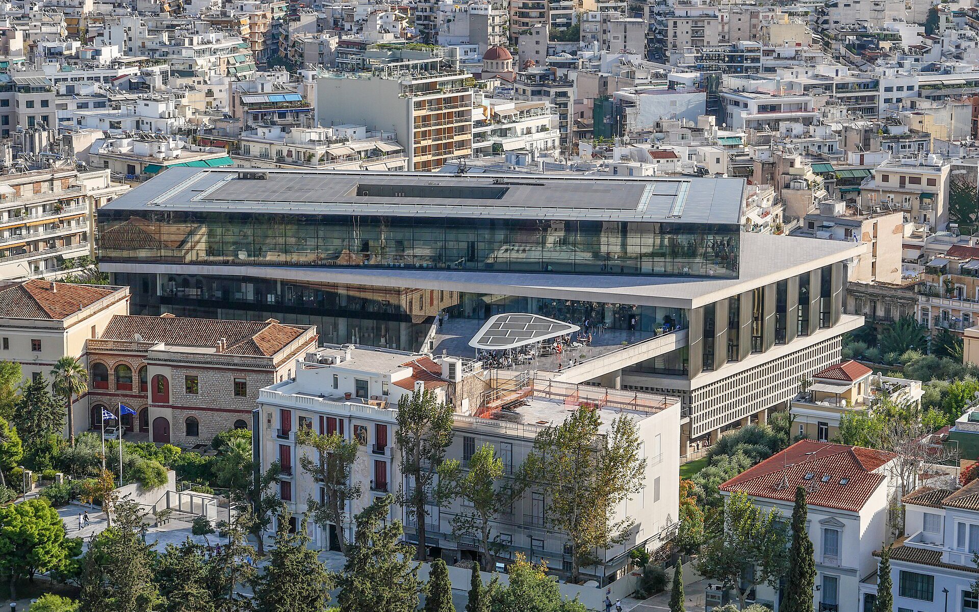 Aerial view of the Acropolis Museum in Athens surrounded by city buildings.