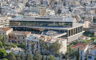 Aerial view of the Acropolis Museum in Athens surrounded by city buildings.