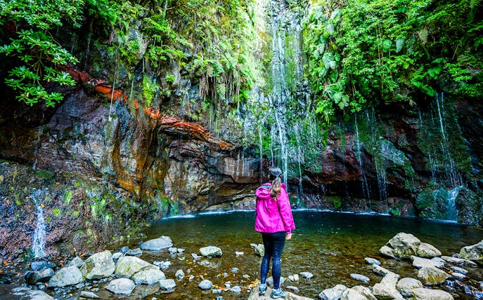 Person standing by a waterfall on the Rabaçal 25 Fountains Levada Walk.