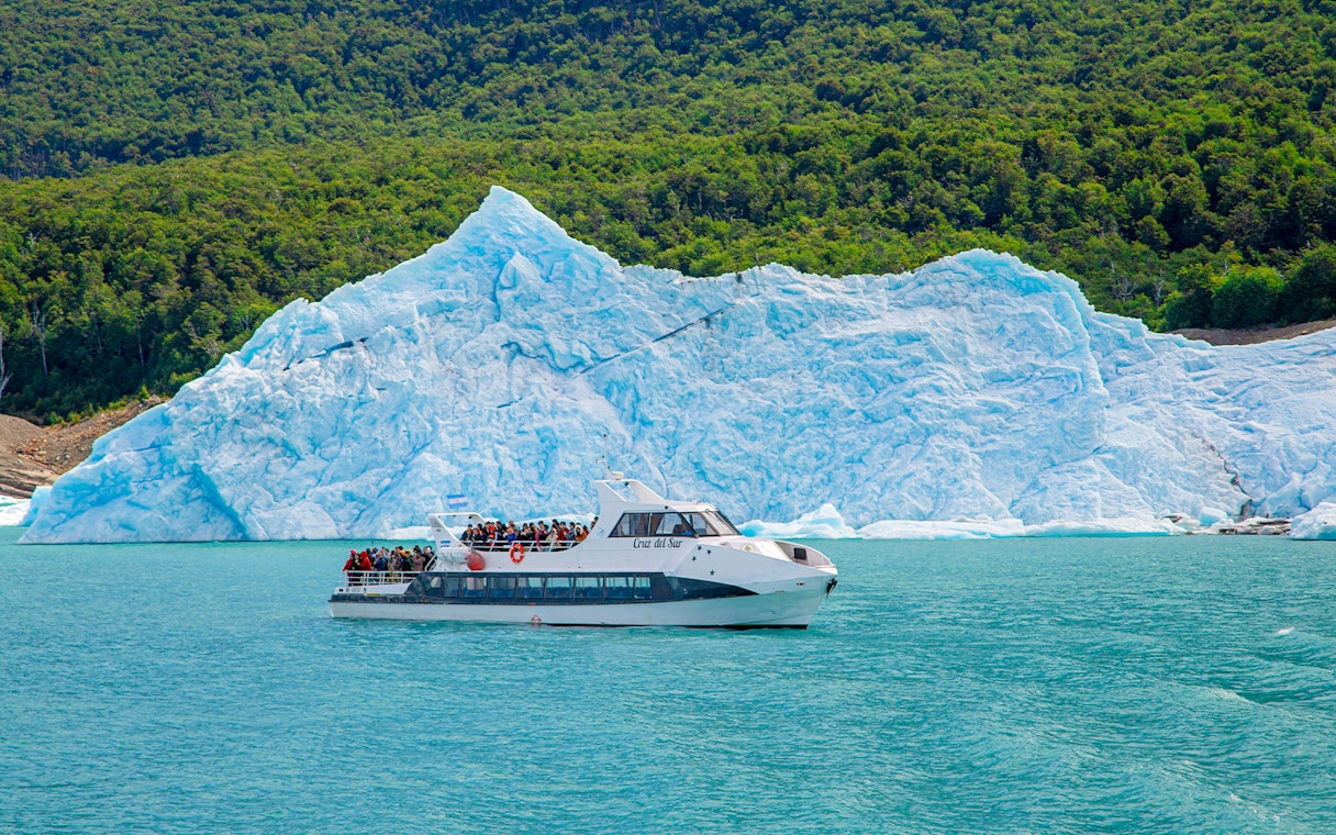 Tourists on a boat tour at Lago Argentino with a glacier backdrop in Los Glaciares National Park, Patagonia.