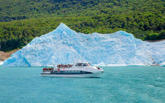 Tourists on a boat tour at Lago Argentino with a glacier backdrop in Los Glaciares National Park, Patagonia.