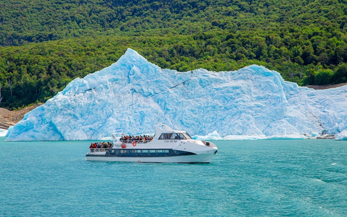 Tourists on a boat tour at Lago Argentino with a glacier backdrop in Los Glaciares National Park, Patagonia.