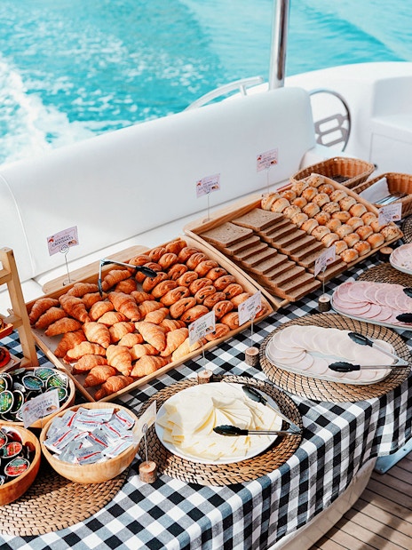 Breakfast buffet on luxury yacht cruise with pastries, fruits, and cold cuts.