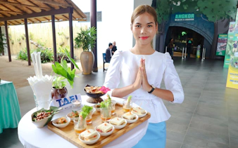 Hostess with traditional greeting at Angkor Wildlife & Aquarium, Siem Reap, with appetizers on table.