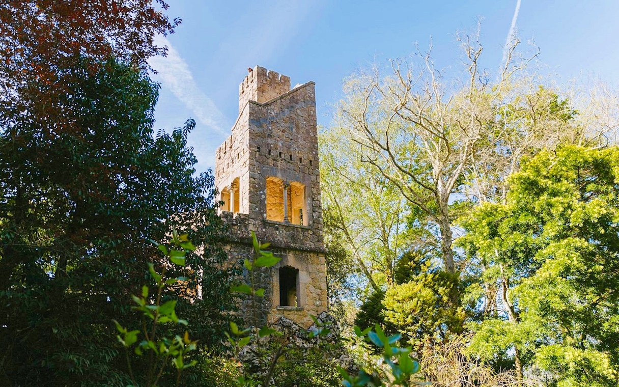 Quinta da Regaleira tower surrounded by lush greenery in Sintra, Portugal.