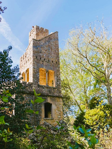 Quinta da Regaleira tower surrounded by lush greenery in Sintra, Portugal.