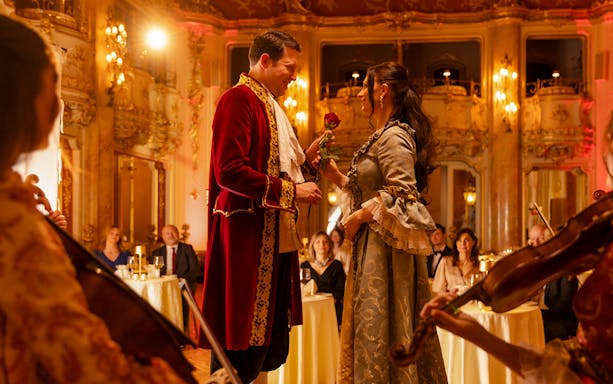 Mozart Dinner Opera in Prague with performers in period costumes exchanging a rose.