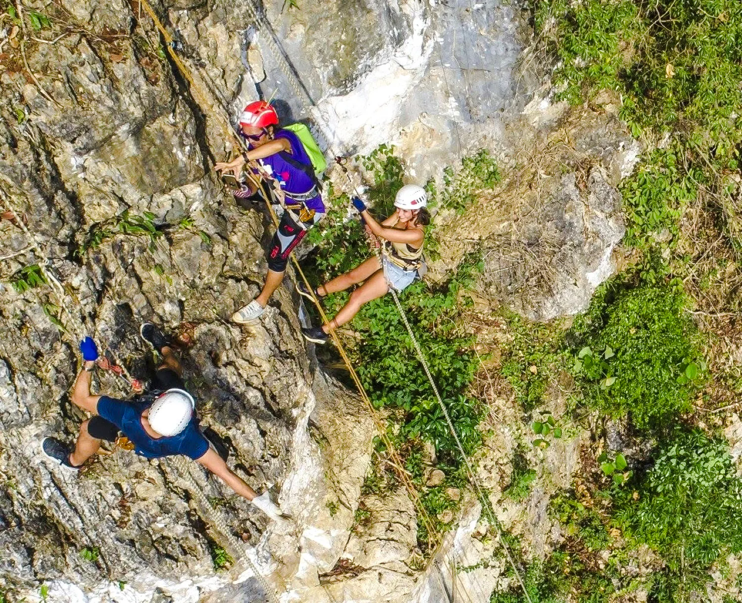 Participants ziplining and abseiling on a rocky cliff in Krabi, Thailand.