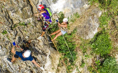 Participants ziplining and abseiling on a rocky cliff in Krabi, Thailand.