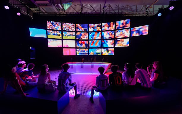 Visitors watching Messi highlights on multiple screens at The Messi Experience in Dubai.