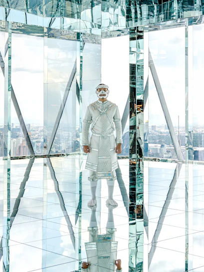 Hanuman statue in mirrored room at Akara Sky, cityscape view in background.