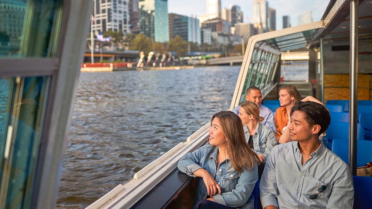Melbourne River Cruise guests enjoying Yarra River views with city skyline in the background.