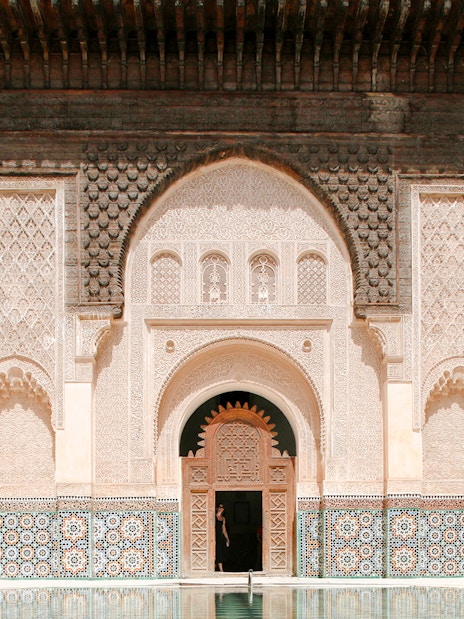 Ben Youssef Madrasa courtyard with intricate carvings and mosaic tiles in Marrakesh, Morocco.