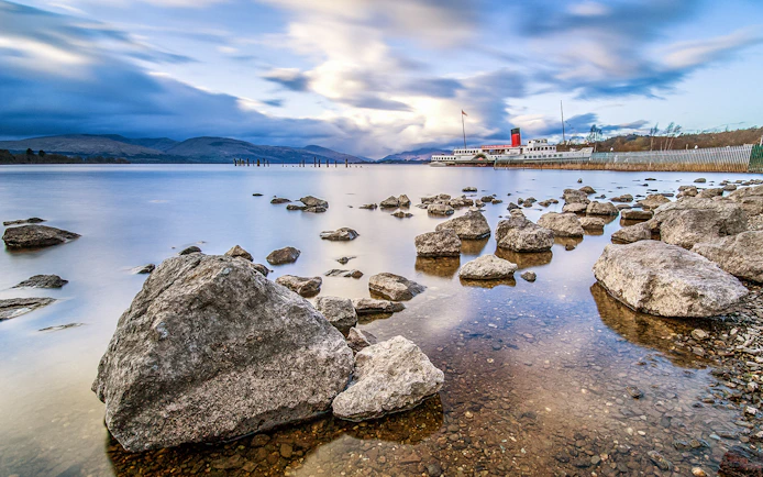 Steamboat on Loch Lomond Lake with rocky shoreline and distant hills.