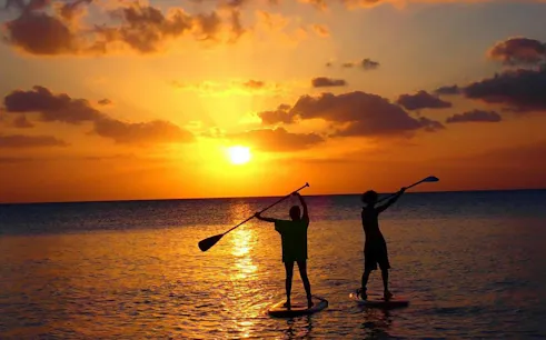 Paddleboarders at sunset on Miyakojima, Okinawa during SUP tour.