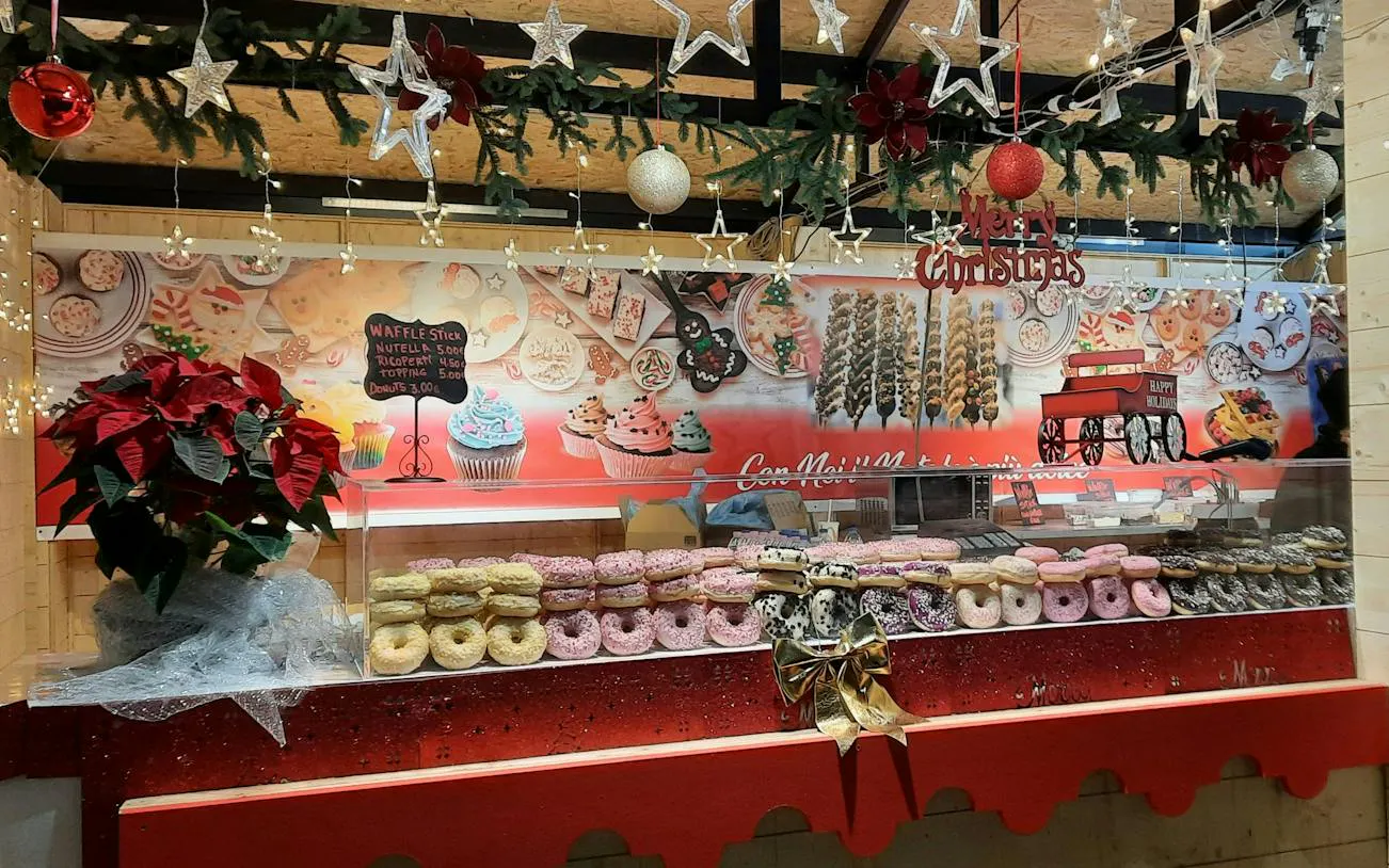 Christmas-themed pastry stall with donuts and decorations in Milan.