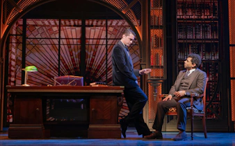 Two actors in a library setting during The Great Gatsby musical on Broadway.