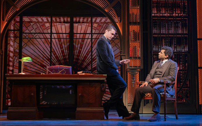 Two actors in a library setting during The Great Gatsby musical on Broadway.