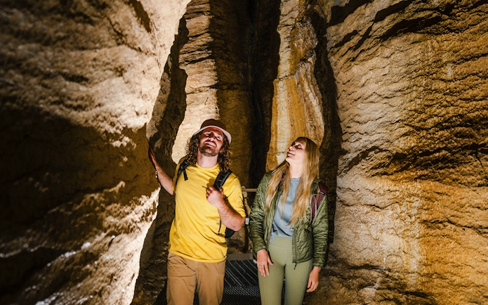 Tourists exploring Te Anau Glowworm Caves with rock formations.
