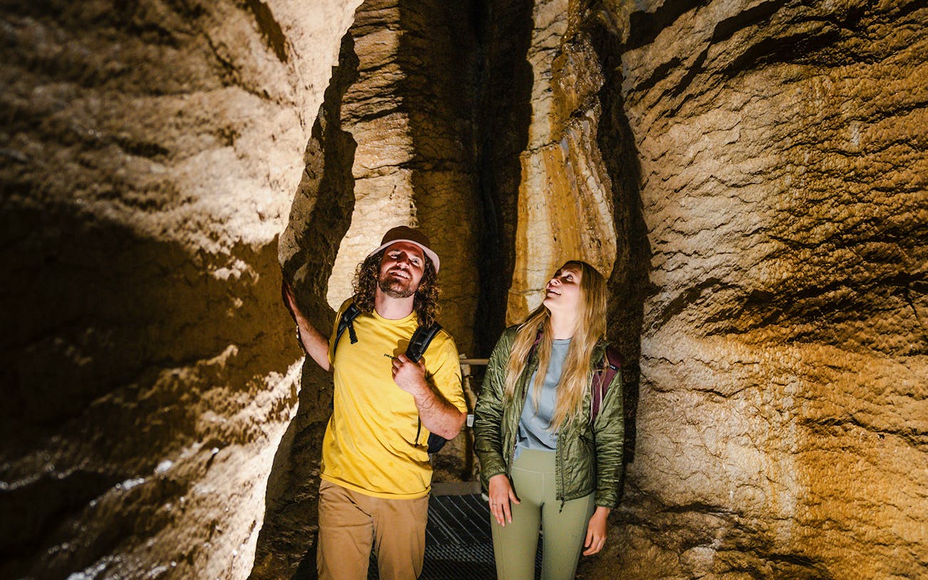 Tourists exploring Te Anau Glowworm Caves with rock formations.