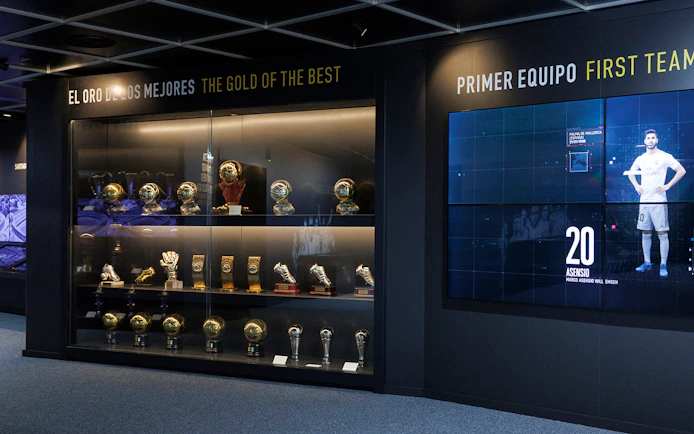 Trophy display at Santiago Bernabéu Stadium museum, featuring football awards and memorabilia.