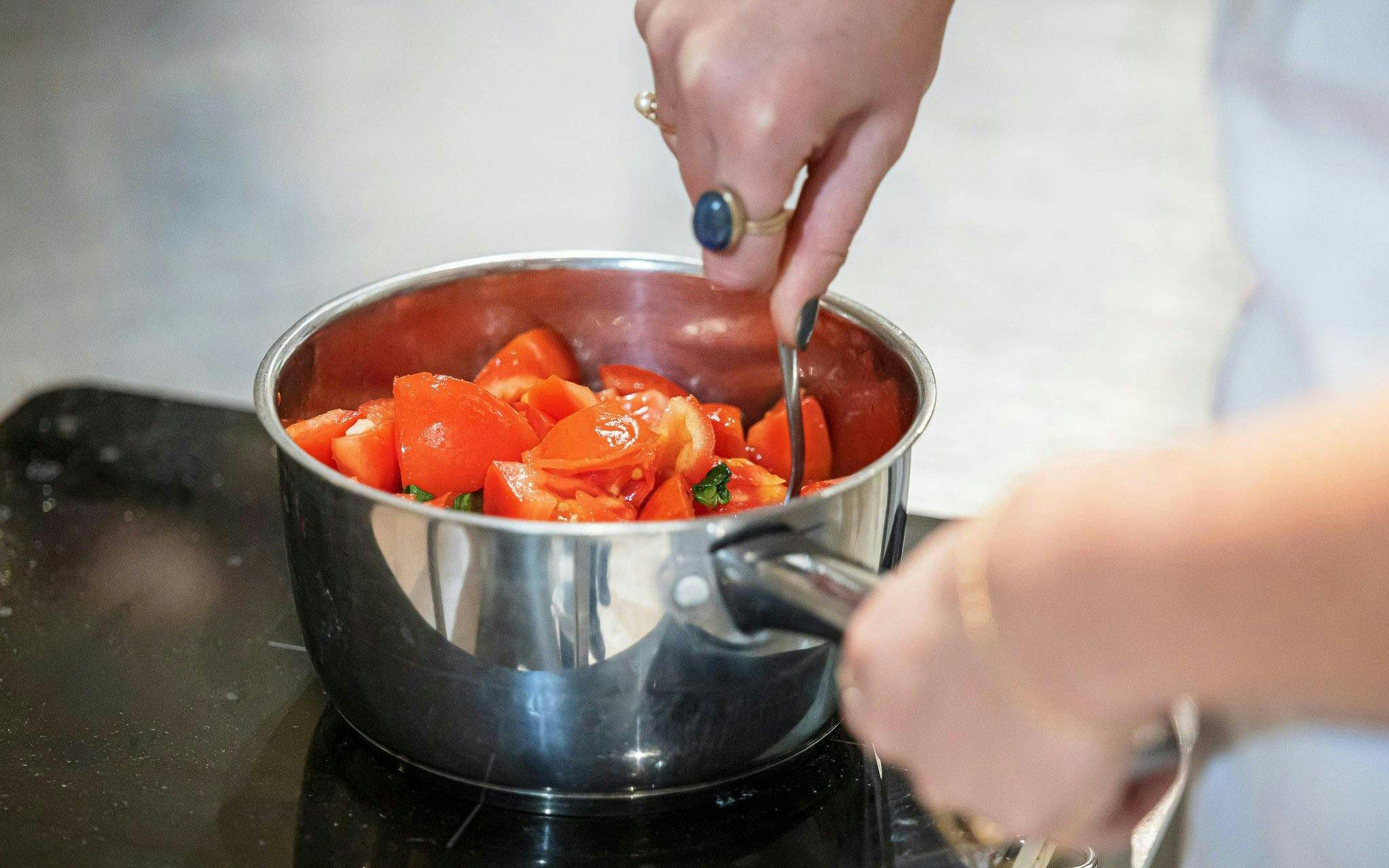 Cooking tomatoes in a pot during a small group class in Florence.