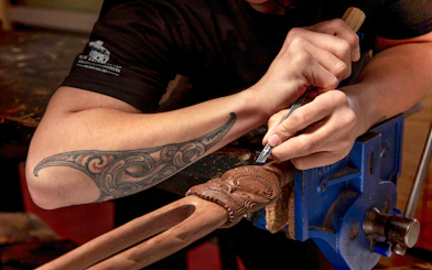 Maori guide carving wood at Te Puia, Rotorua, New Zealand.