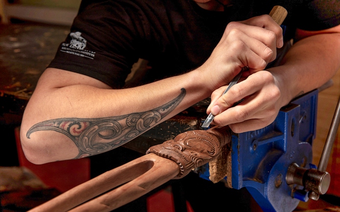 Maori guide carving wood at Te Puia, Rotorua, New Zealand.