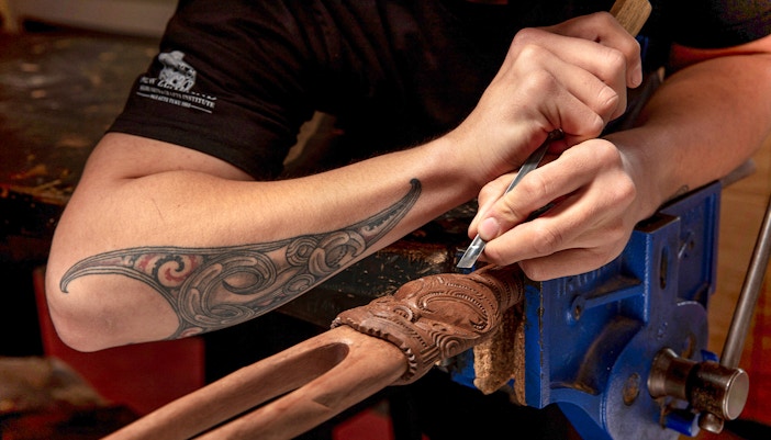 Maori guide carving wood at Te Puia, Rotorua, New Zealand.