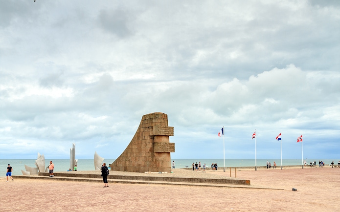 Omaha Beach monument with international flags, Normandy coast, related to D-Day landings.