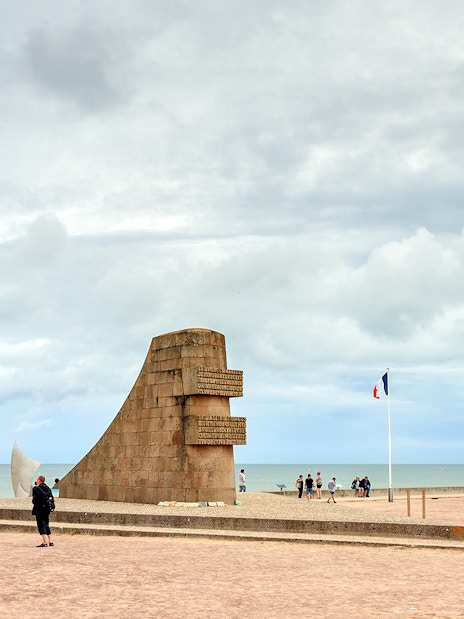 Omaha Beach monument with international flags, Normandy coast, related to D-Day landings.