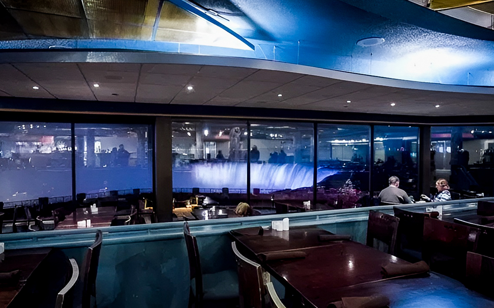 Dining area with view of illuminated Horseshoe Falls through large windows.