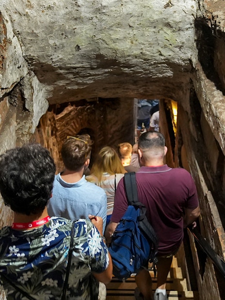 Visitors descending stairs into Capuchin Crypt with guide in Rome.