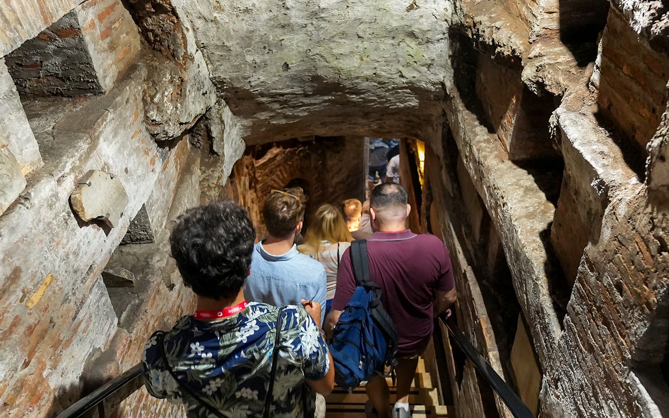 Visitors descending stairs into Capuchin Crypt with guide in Rome.