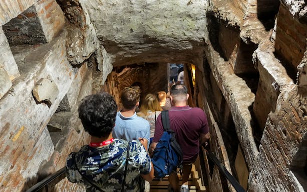 Visitors descending stairs into Capuchin Crypt with guide in Rome.