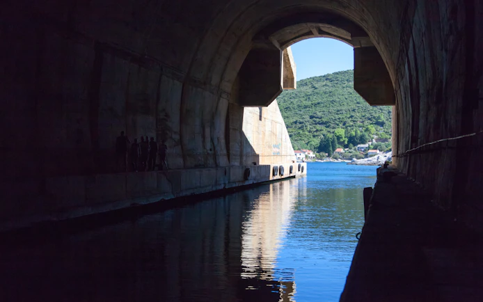 Yugoslav Underground Boat Shelter entrance with view of water and hillside.