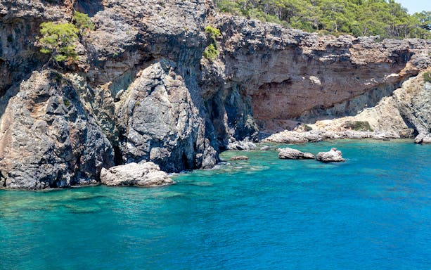 Rocky coastline and clear blue waters near Phaselis on a boat trip from Antalya.