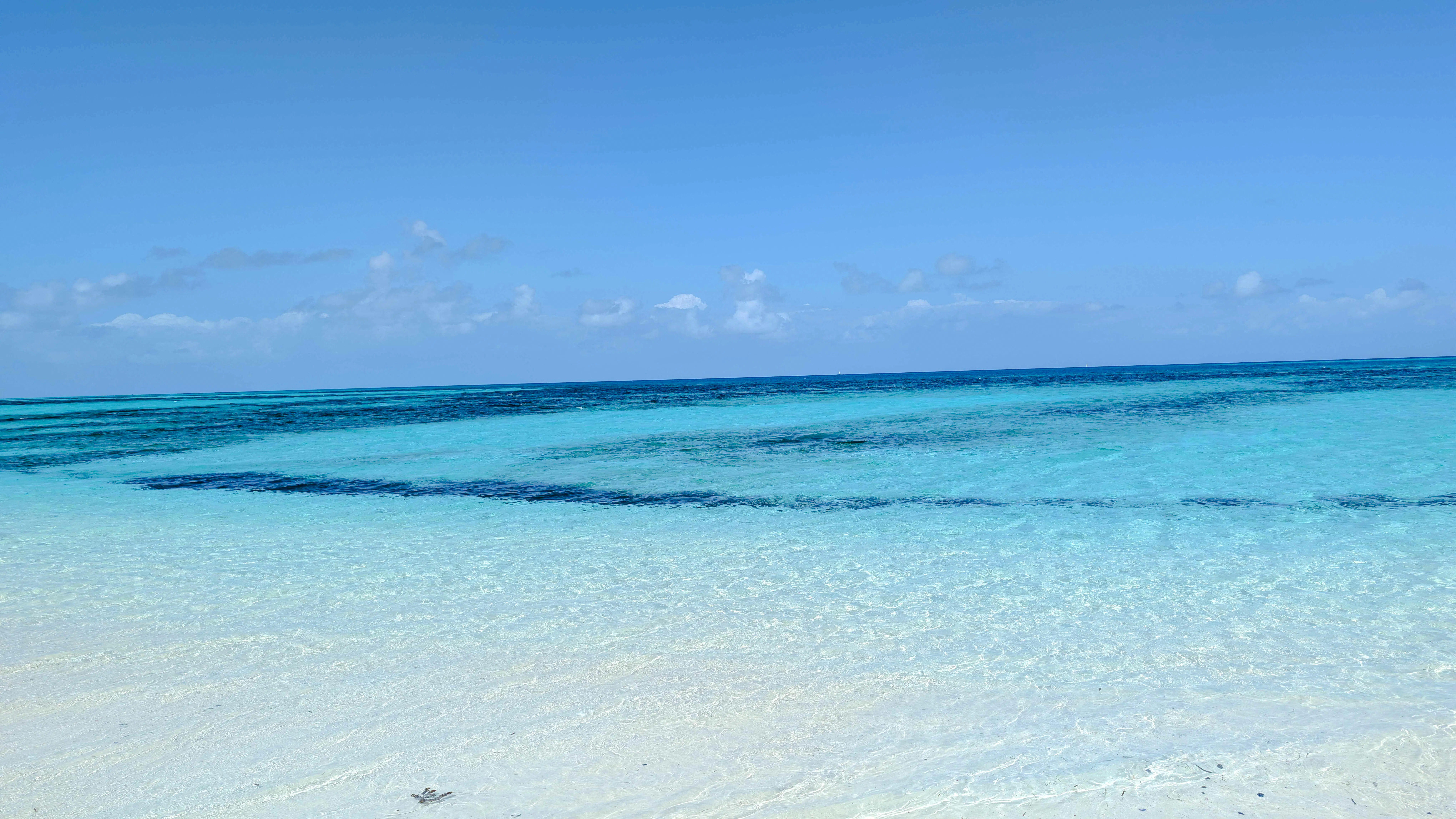 Clear turquoise waters of a Zanzibar sandbank under a blue sky.