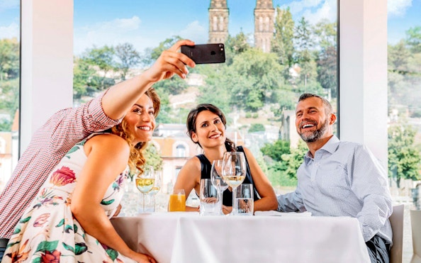 Group taking a selfie on Vltava River cruise with Prague skyline in background.