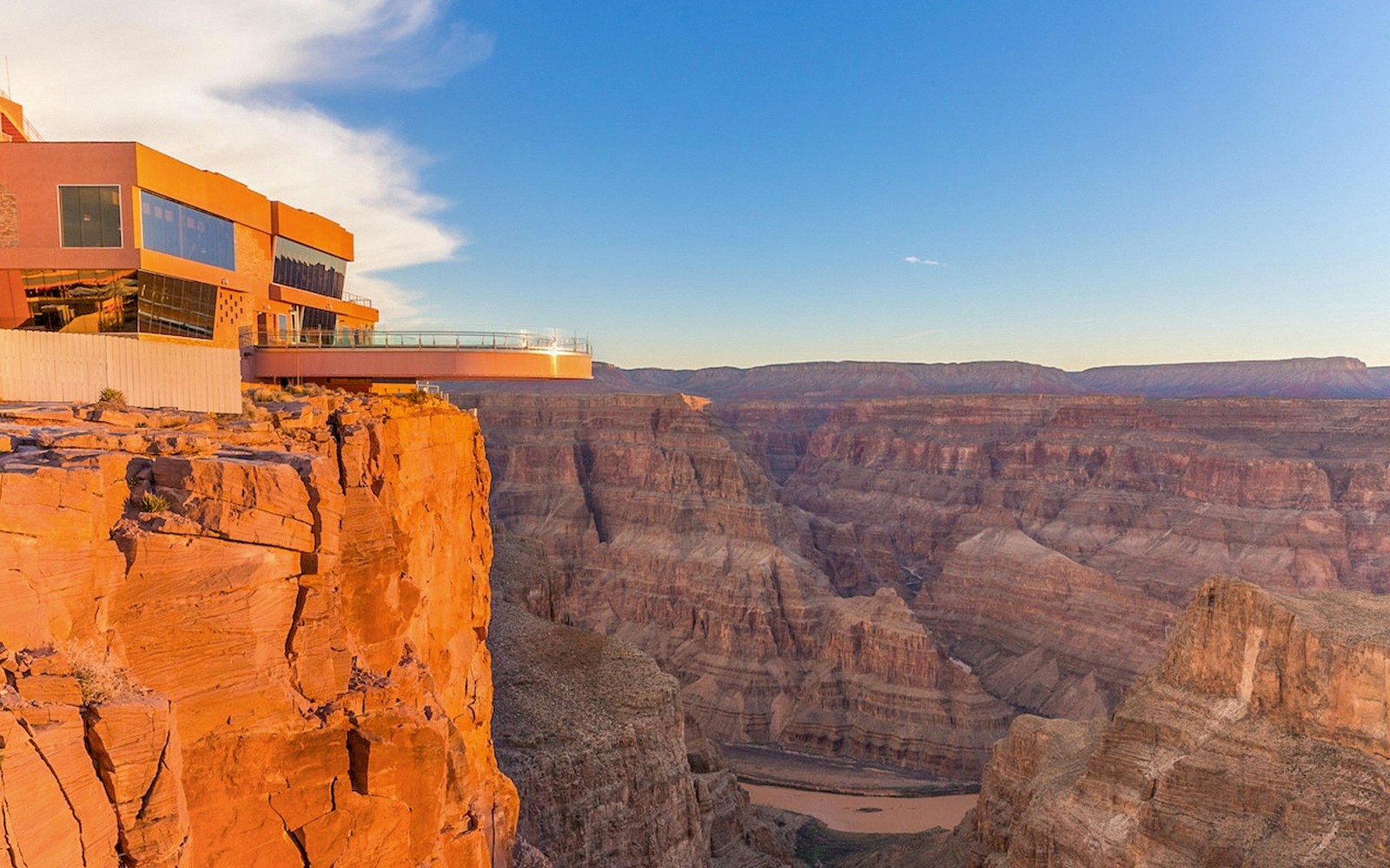 Tourists viewing the Grand Canyon West Rim from an observation point with a clear sky.