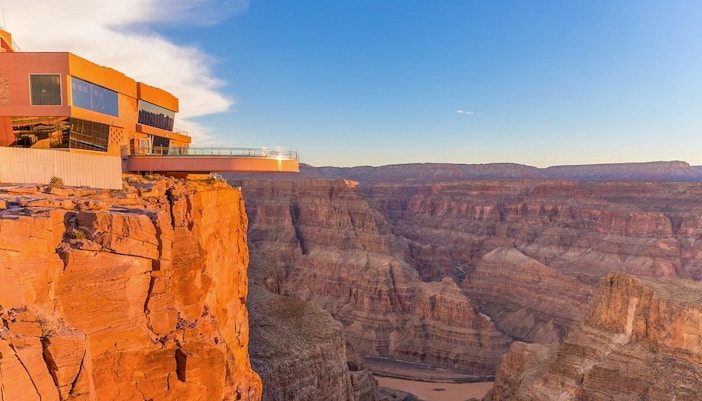 Tourists viewing the Grand Canyon West Rim from an observation point with a clear sky.