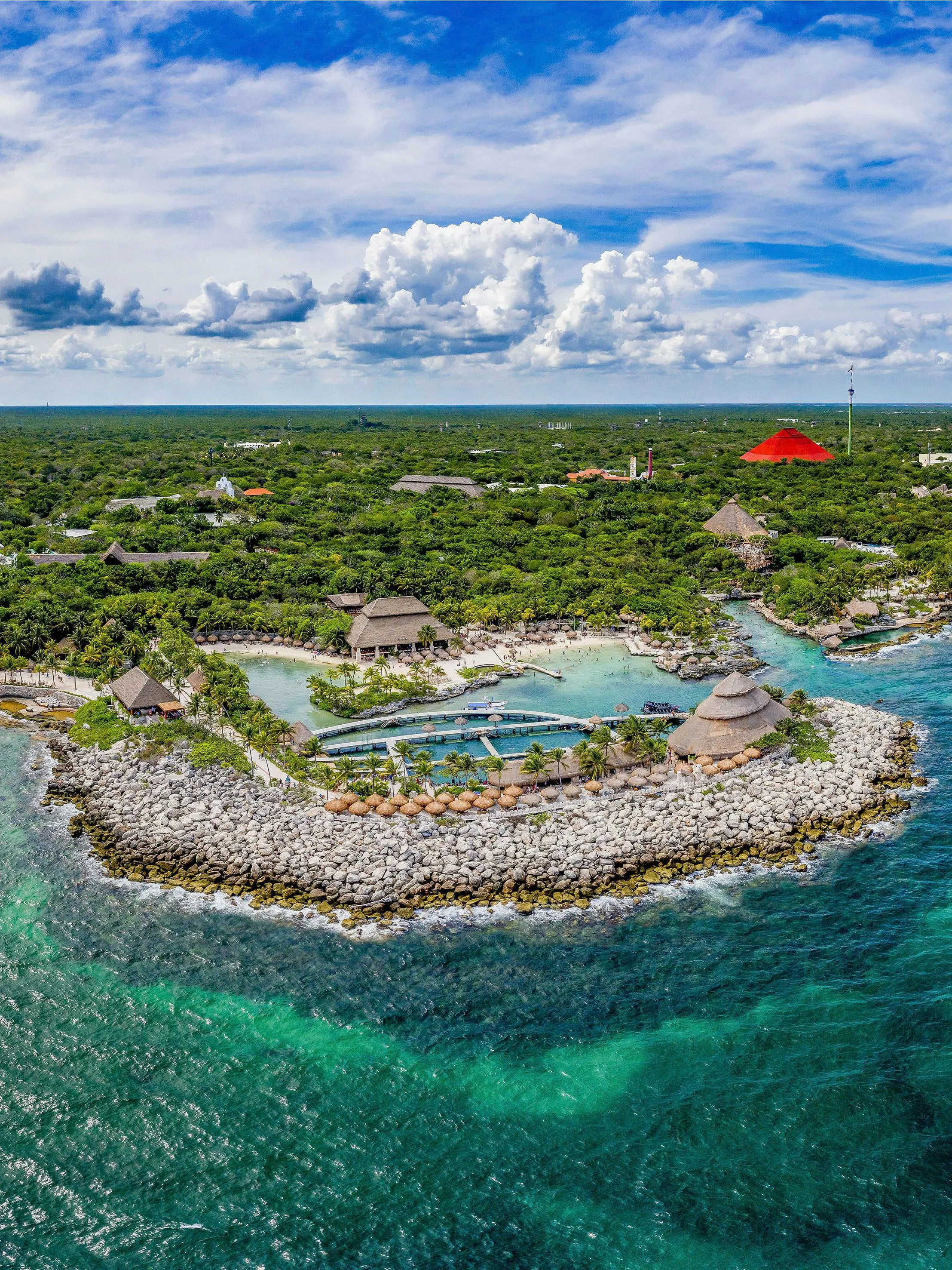 Aerial view of Xcaret Park's coastline with lush greenery and turquoise waters in Mexico.