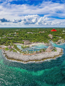 Aerial view of Xcaret Park's coastline with lush greenery and turquoise waters in Mexico.
