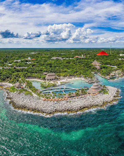 Aerial view of Xcaret Park's coastline with lush greenery and turquoise waters in Mexico.